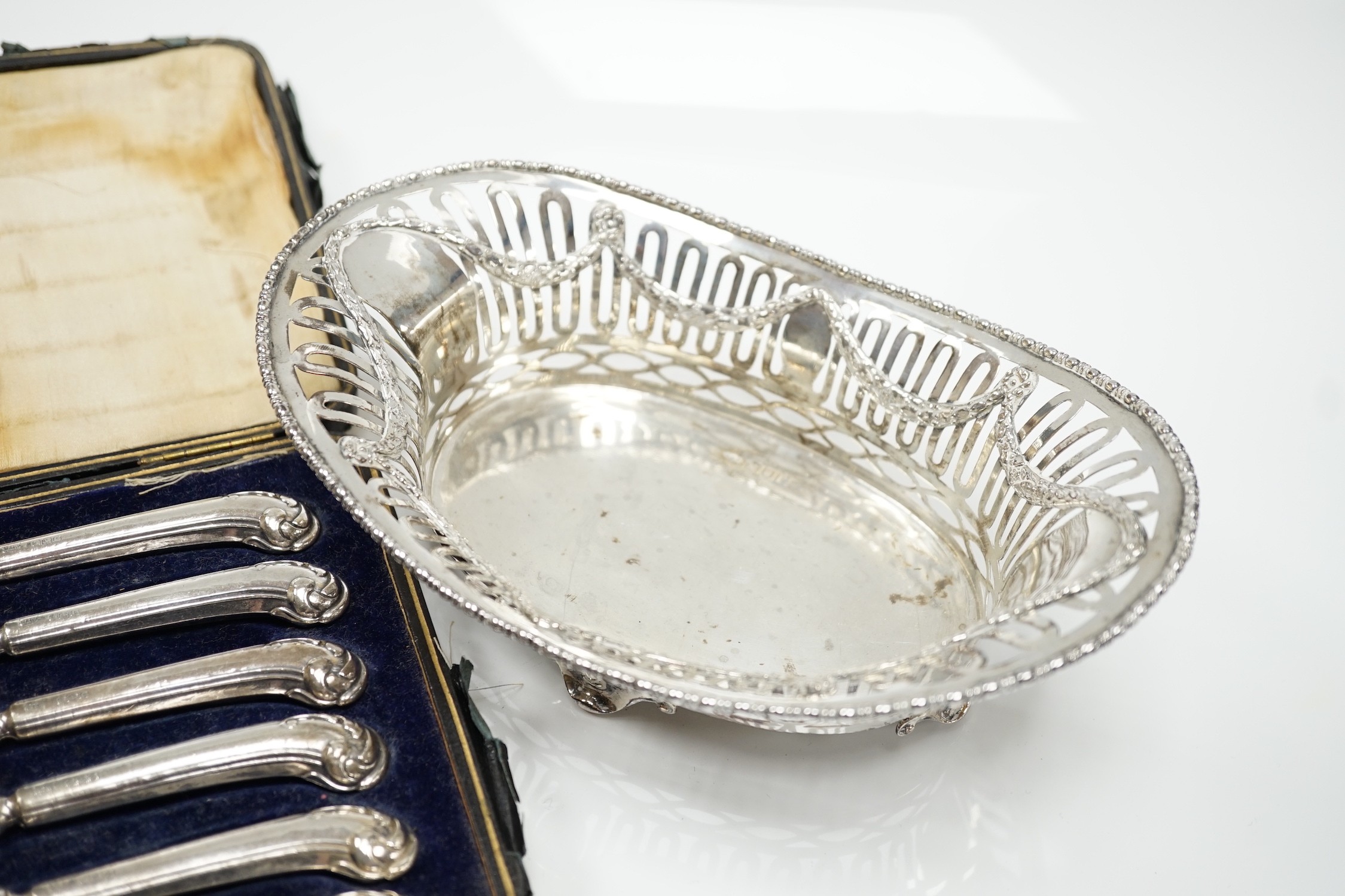 A George V pierced silver oval bowl, 21cm, London, 1912, 5.5oz and a cased set of six silver pistol handled steel tea knives.